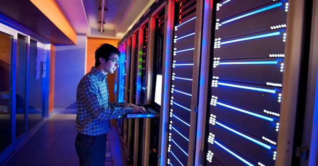 Photo of person working in colorfully lit data center.