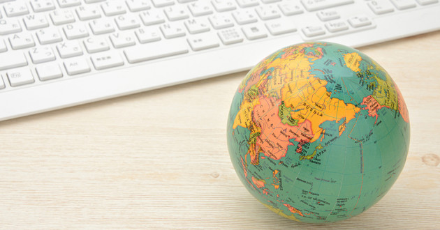 A small globe on a desk next to a computer keyboard: cyber resilience