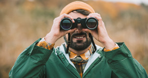 A man using binoculars outdoors: threat hunting