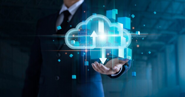 Businessman in a blue suit holding his hand out & a digital cloud image with arrows hovering