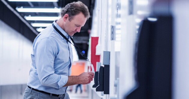 A professional man using an ID badge to scan into a locked room