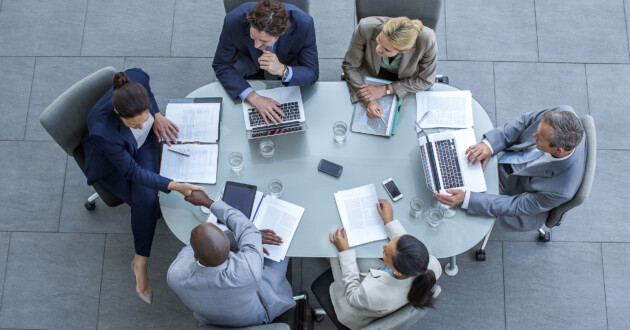 High angle view of businesspeople having a meeting with individual laptops at conference table in office