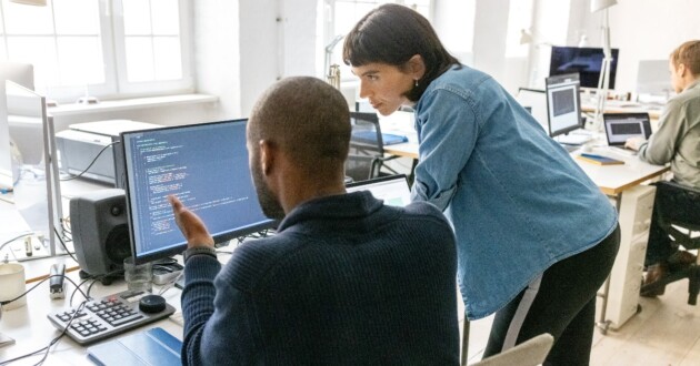 2 software developers at a desk reviewing & discussing code on a computer