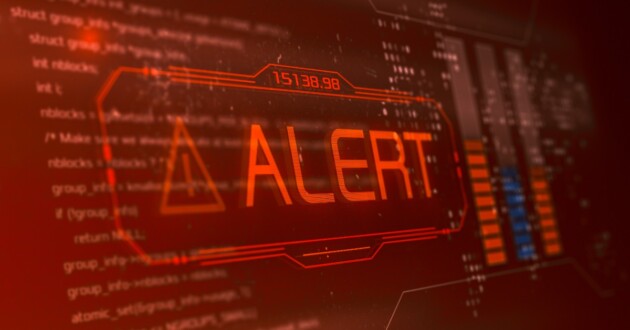 Closeup on a red computer screen displaying code covered by a large ALERT message