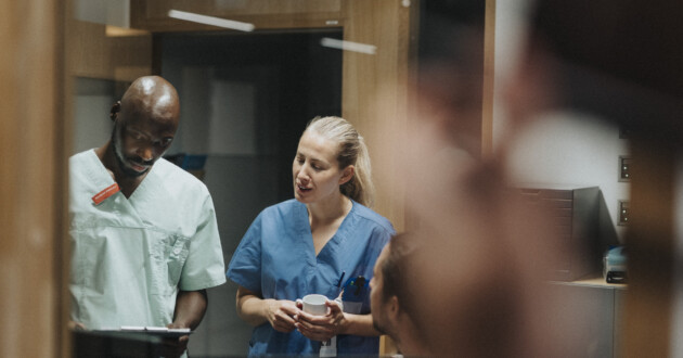 Medical professional colleagues in scrubs talking in a hospital hallway